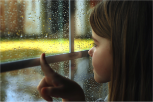 girl by window looking at rainy day